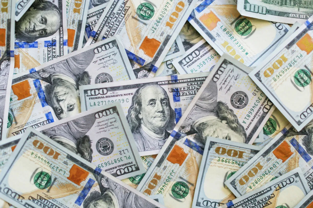 Stacked US dollar bills illustrating $100,000 invested growth over 20 years